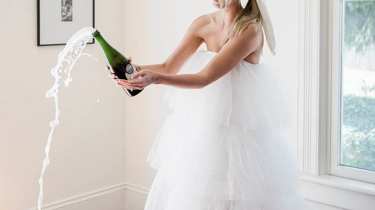 model popping champagne in a dramatic tulle wedding dress