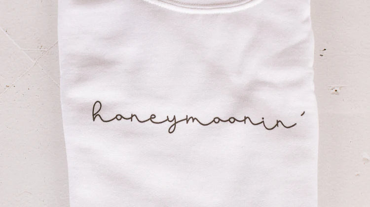 a white embroidered “honeymoonin’” sweatshirt