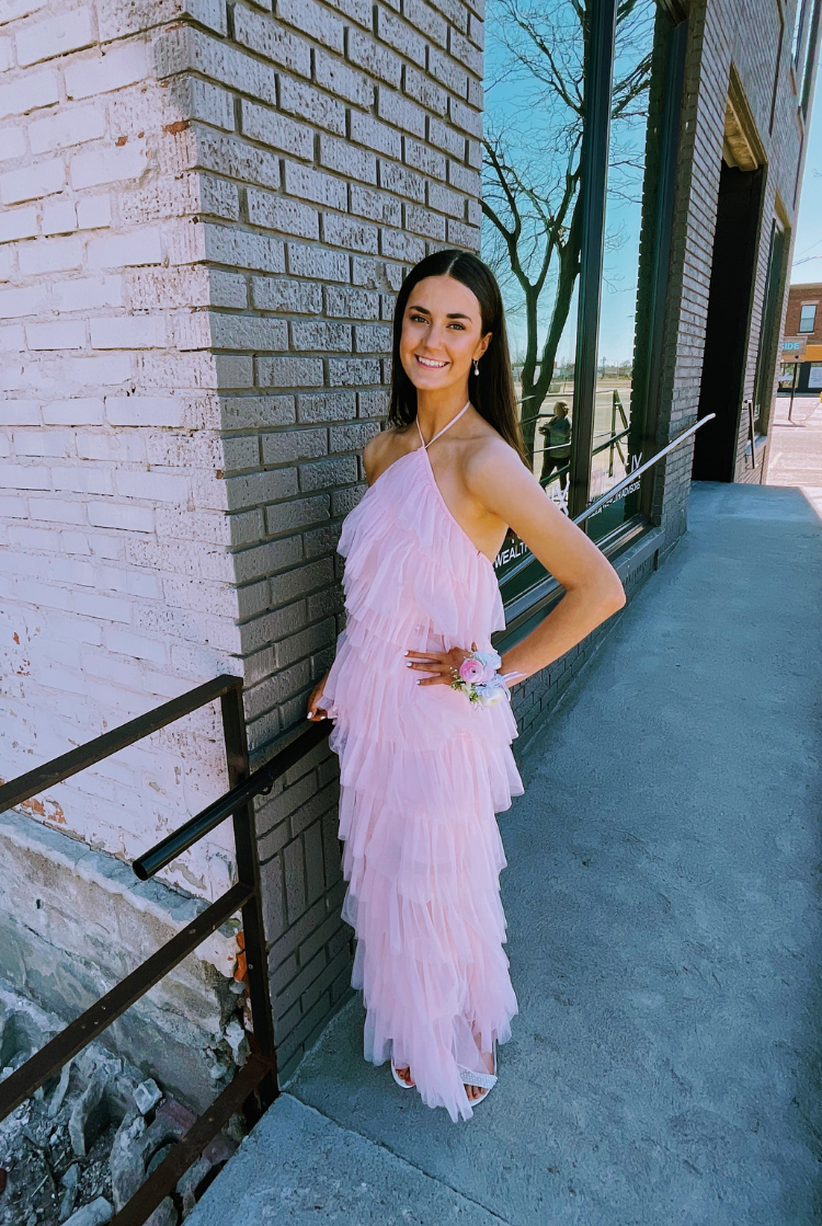 a woman in a pink tulle dress posing in front of a brick wall.