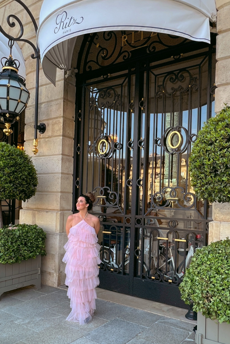 a woman in a pink tulle dress in front of a large door.