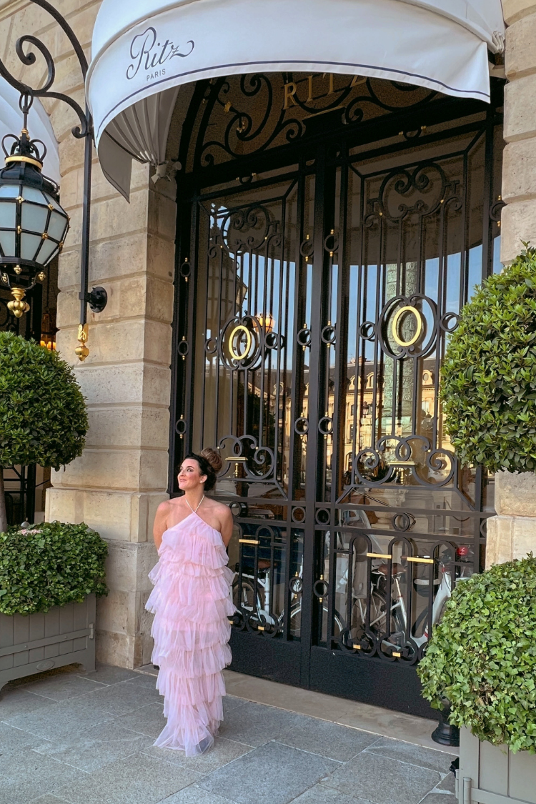 a woman in a pink tulle dress in front of a large door.