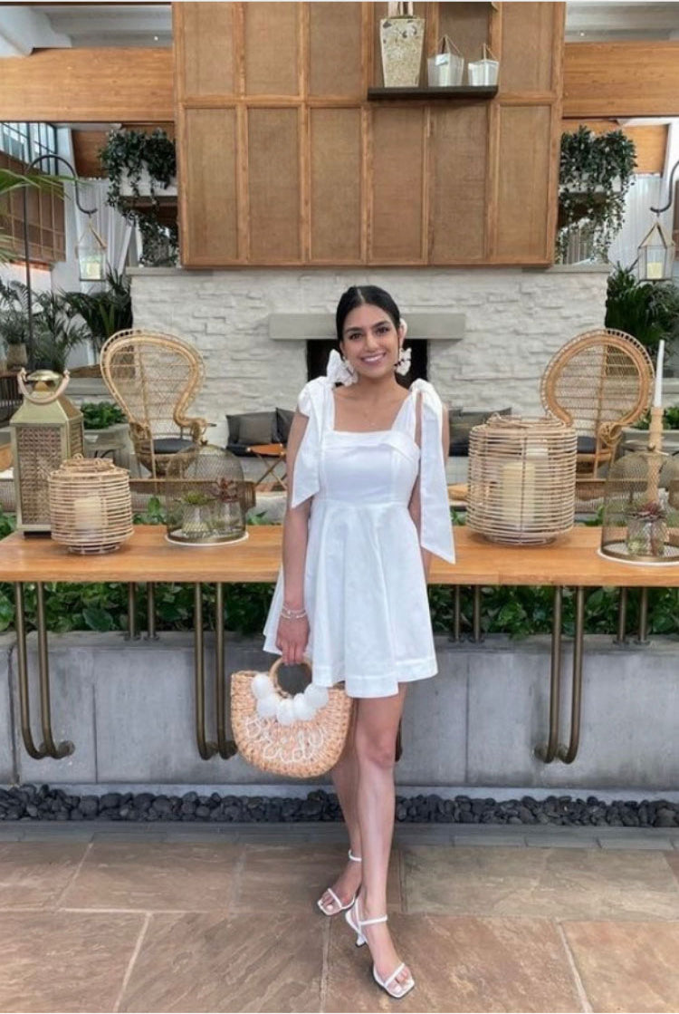 a woman in a short white dress and white shoes in front of a table.