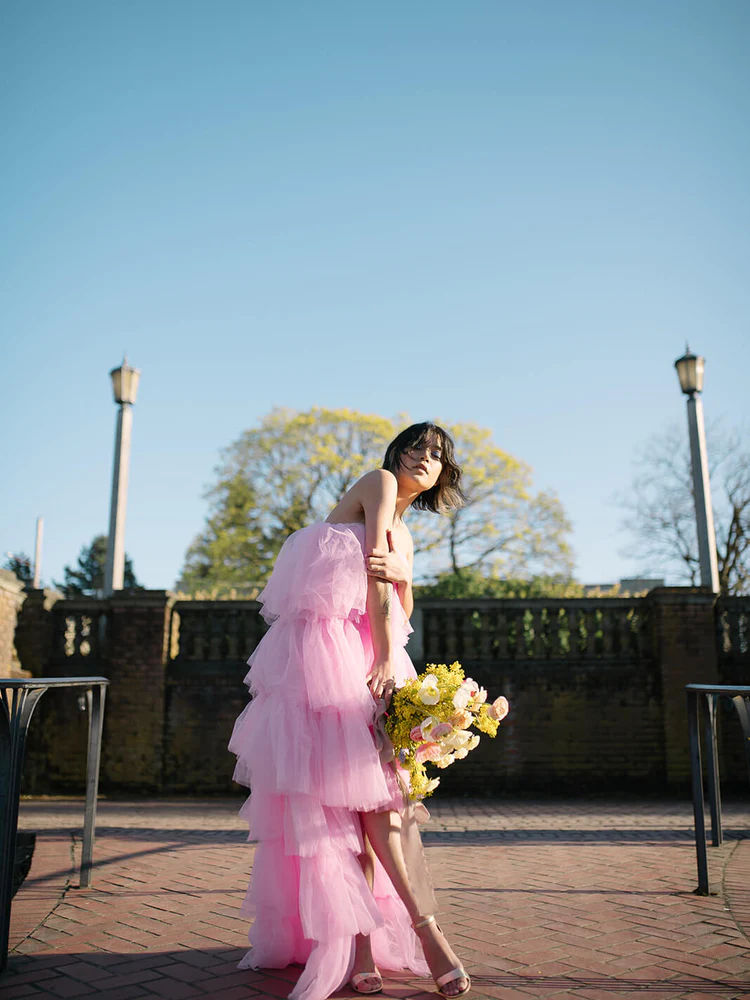 model holding flowers wearing a pink tulle maxi dress