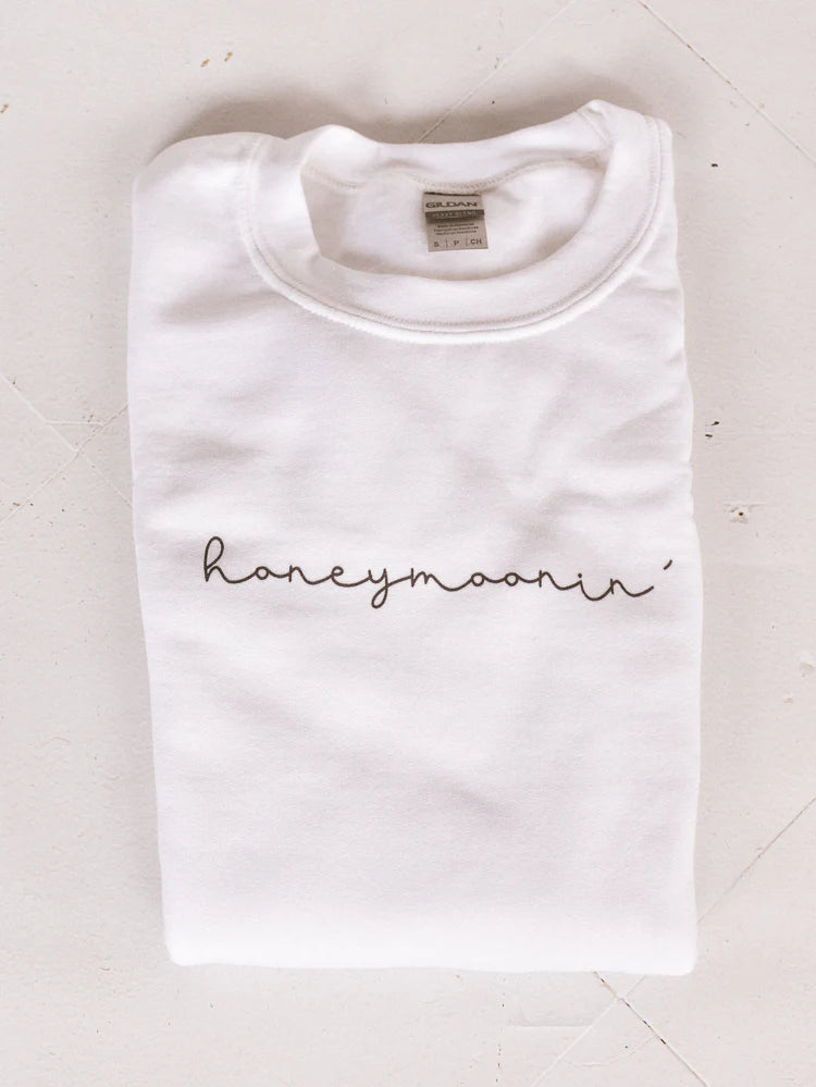 a white embroidered “honeymoonin’” sweatshirt