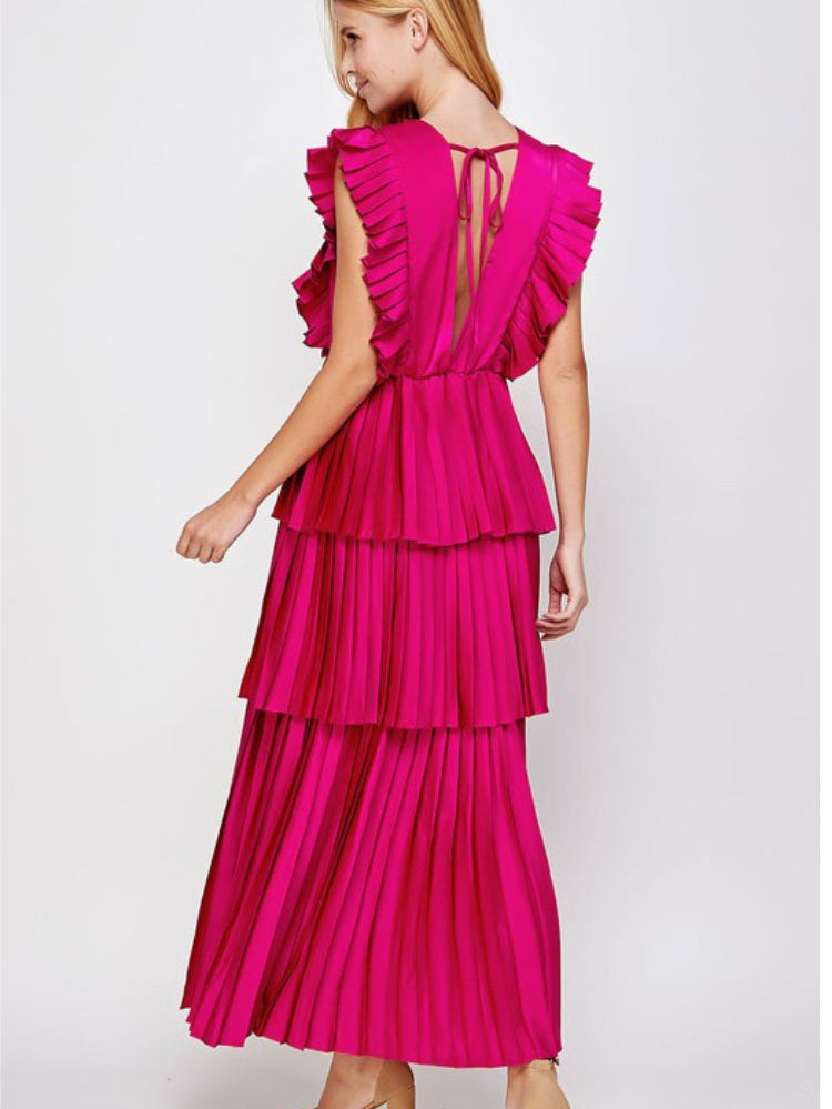 a model in a pink tiered maxi dress facing away from the camera. 