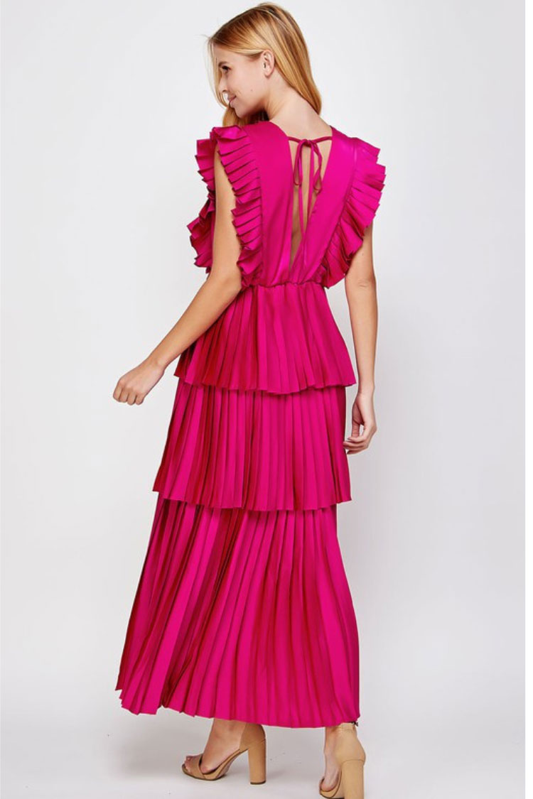 a model in a pink tiered maxi dress facing away from the camera. 