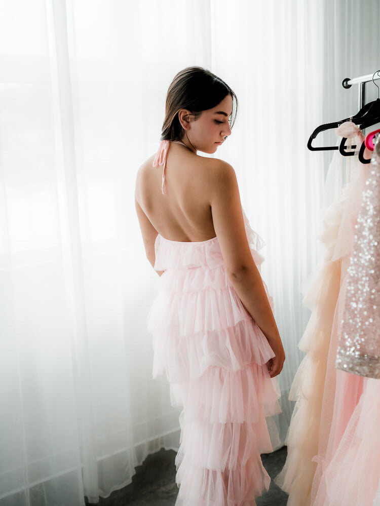  a model in a pink tulle dress facing away from the camera.
