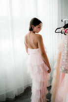  a model in a pink tulle dress facing away from the camera.