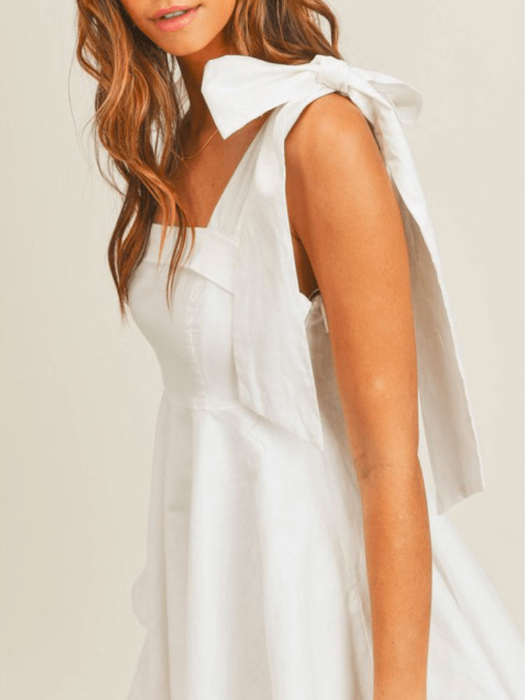 model in a white dress with bow tie shoulders.
