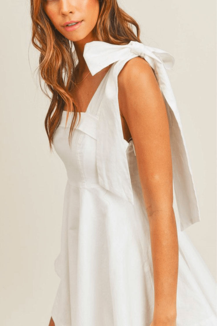 model in a white dress with bow tie shoulders.