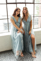 two women sitting down in blue dresses with glitter.