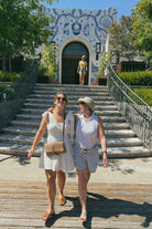 two women walking in front of stone stairs.