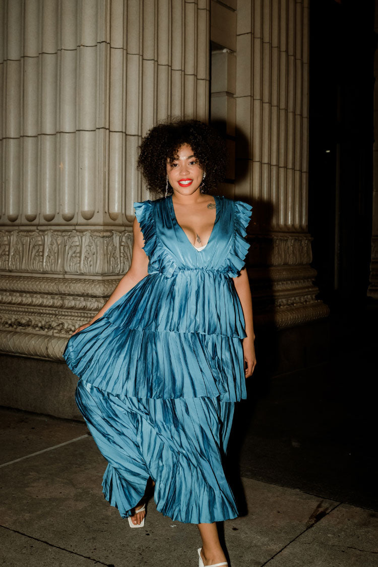  a woman wearing a blue tiered maxi dress at night.