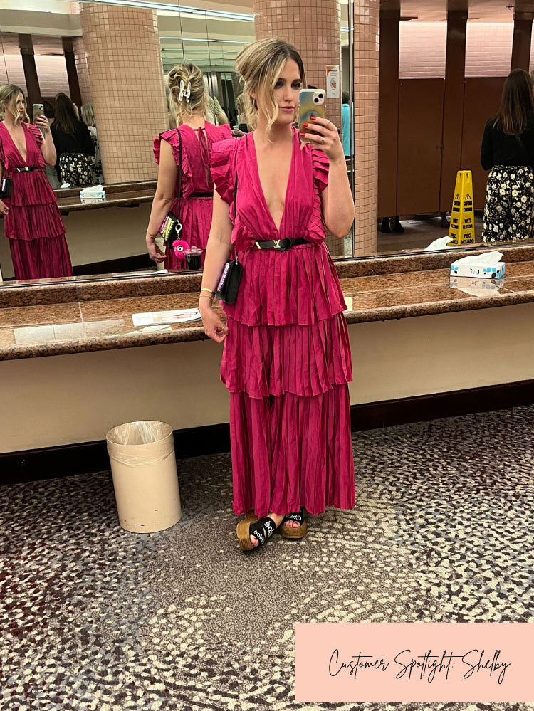 a woman taking a selfie in the mirror in a pink tiered maxi dress.
