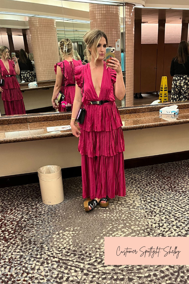 a woman taking a selfie in the mirror in a pink tiered maxi dress.