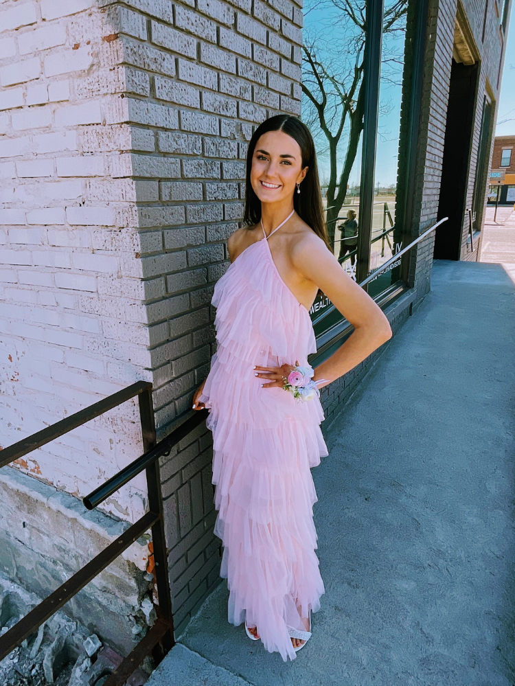 a woman in a pink tulle dress posing in front of a brick wall.