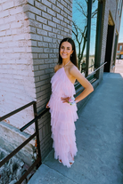 a woman in a pink tulle dress posing in front of a brick wall.