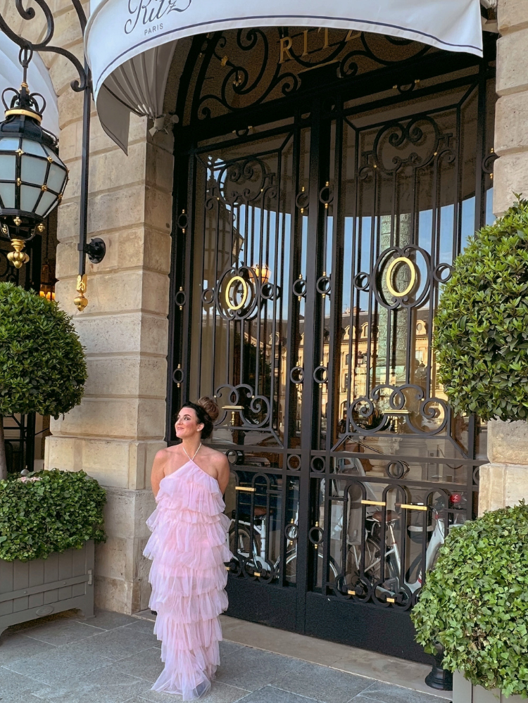  a woman in a pink tulle dress in front of a large door.