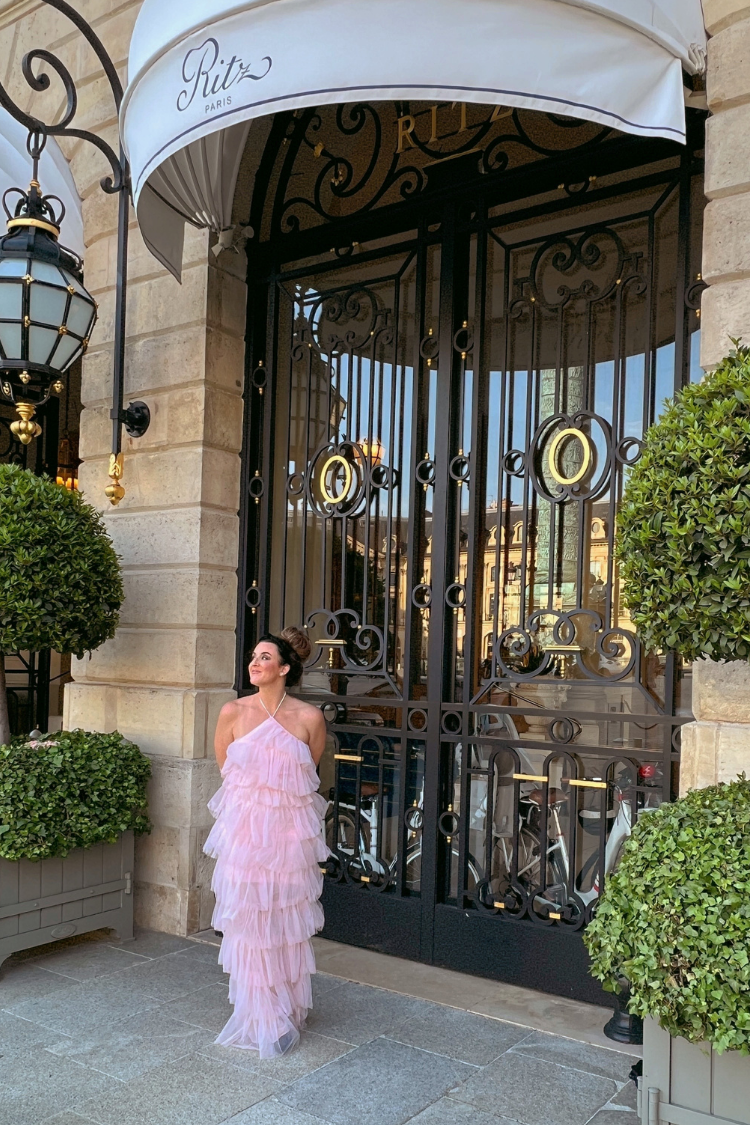  a woman in a pink tulle dress in front of a large door.